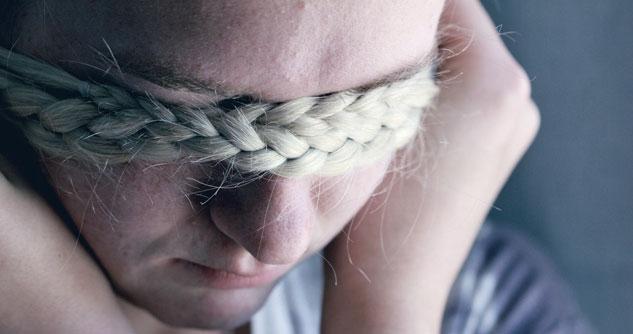 Sad girl covers her eyes with her own thick blonde braid