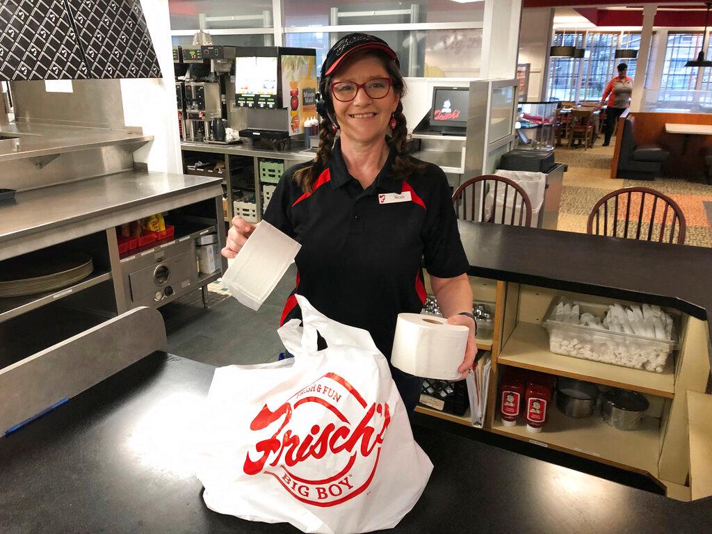 Frisch's Big Boy restaurant employee Nicole Cox bags up an order of toilet paper, among in-demand items including milk and bread the double-decker burger chain is now offering during the coronavirus outbreak in Cincinnati