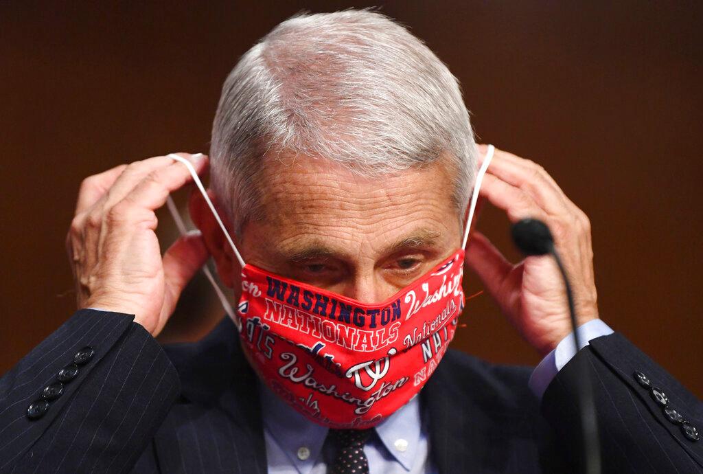 Dr. Anthony Fauci, director of the National Institute for Allergy and Infectious Diseases, lowers his face mask as he prepares to testify before a Senate Health, Education, Labor and Pensions Committee 