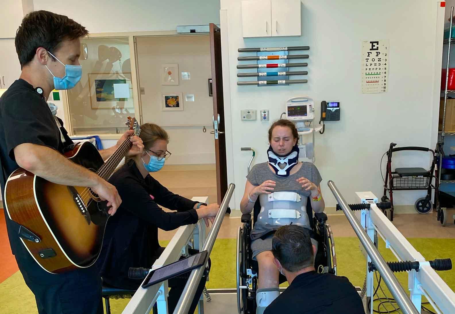 One of the medical professionals plays worship music for Ancil during a physical therapy session  