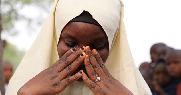 Nigerian schoolgirl with head covering, praying
