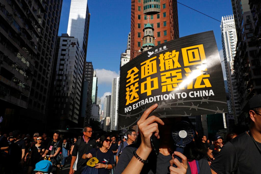 Protesters march with a card that reads "Fully withdraw the extradition to China evil law" in Hong Kong on Sunday, July 21, 2019. Tens of thousands of Hong Kong protesters marched from a public park to call for an independent investigation into police tactics. 
