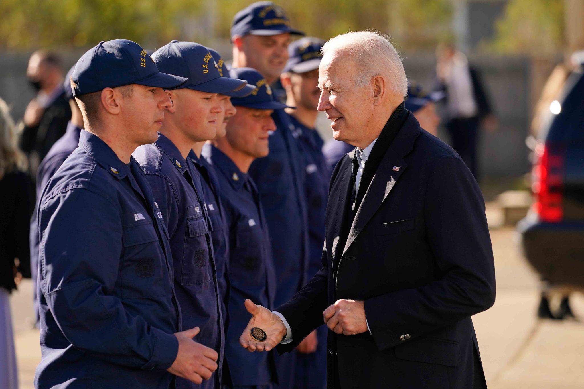 President Joe Biden hands out a challenge coin as he speaks with members of the coast guard at the United States Coast Guard Station Brant Point in Nantucket, Mass., Thursday, Nov. 25, 2021.