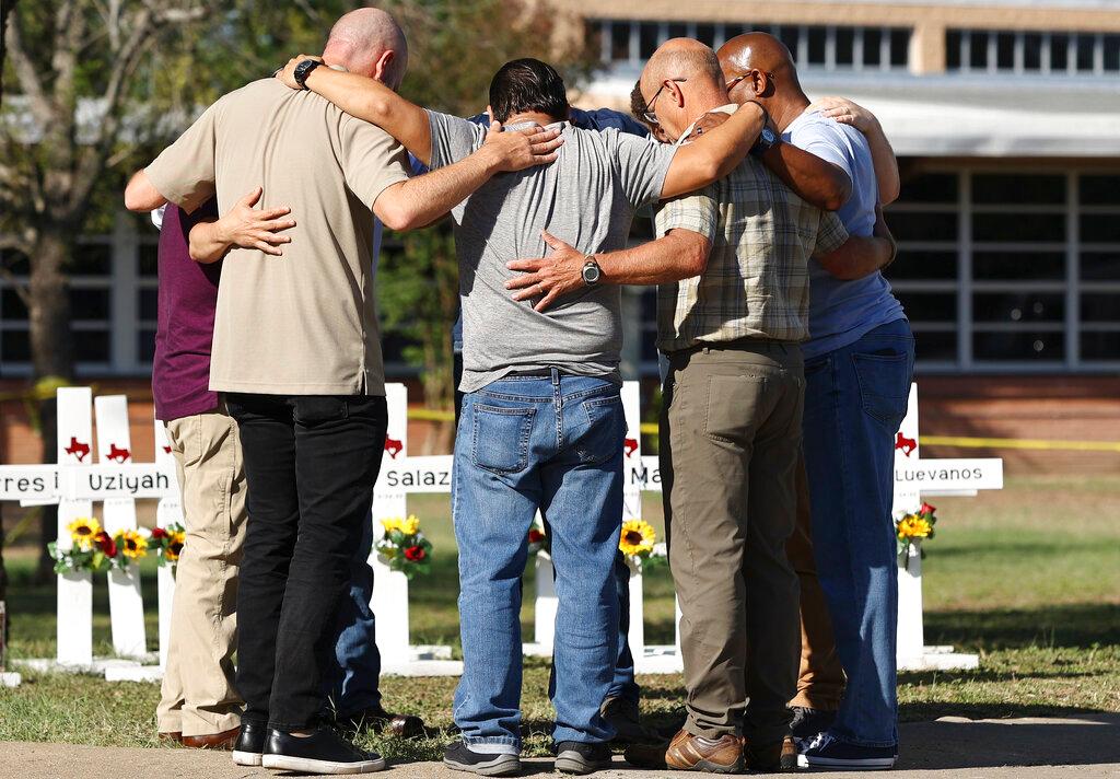 Men form a prayer circle at a memorial site for the victims of the Robb Elementary School shooting