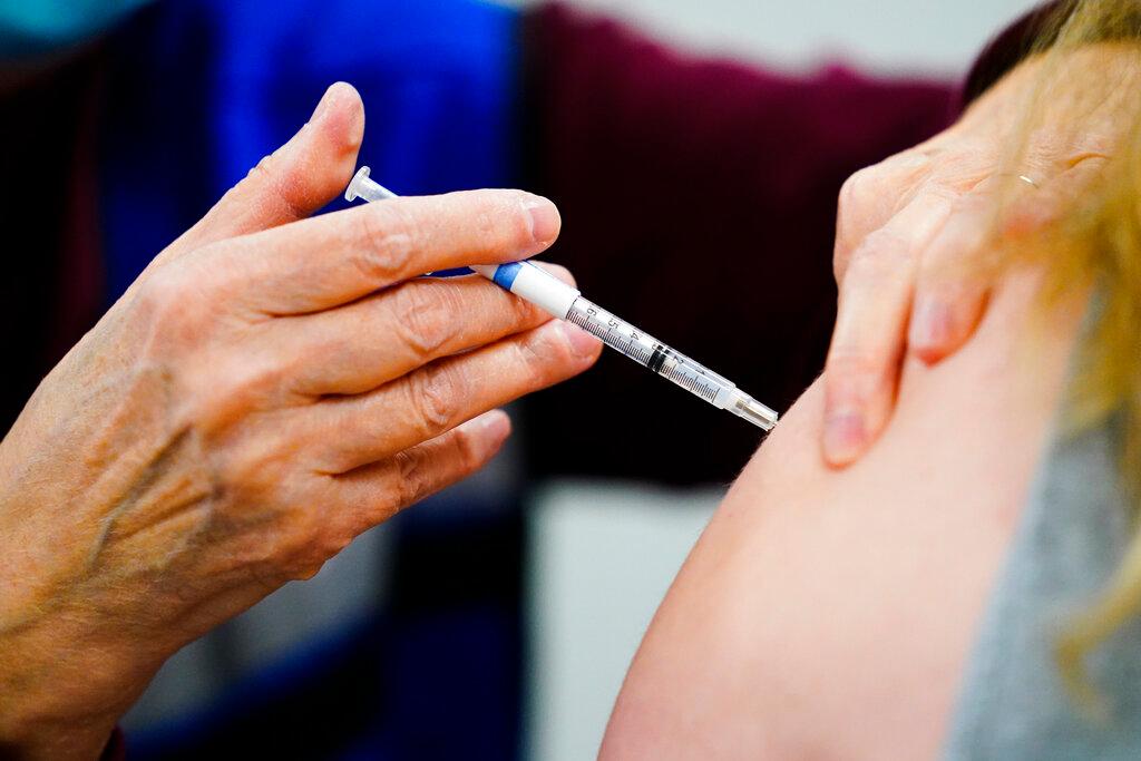 A health worker administers a dose of a COVID-19 vaccine
