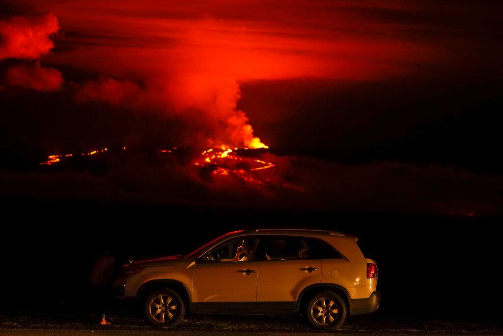 A man talks on a phone in his car alongside Saddle Road as the Mauna Loa volcano erupts 